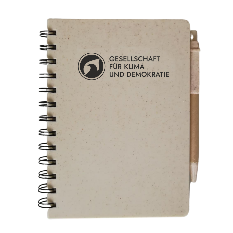 Notizbuch mit Kugelschreiber und dem neuen Logo "Gesellschaft für Klima und Demokratie"